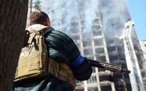 An armed man in a bulletproof vest is seen at the site of shelling of a residential building by the Russian troops in Svyatoshyn district of Kyiv, capital of Ukraine, on March 15, 2022.