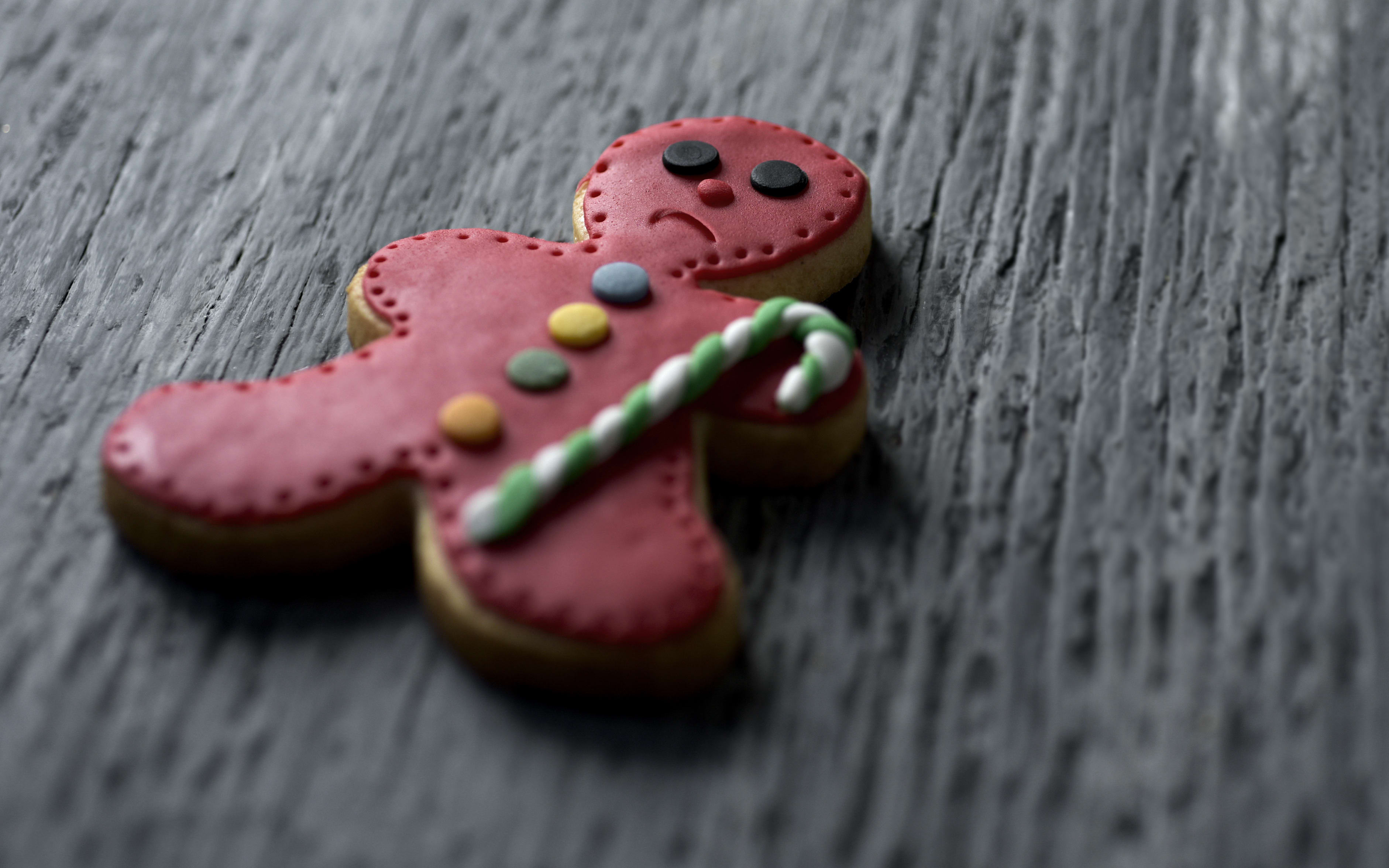 closeup of a sad gingerbread man on a rustic wooden surface, with a negative space