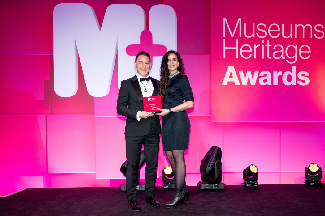 ​Simon Gould, Head of Exhibitions accepting MOTAT'S award from MC and BBC host Ella Al-Shamahi.