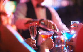 Hands of young people holding martini and champagne in the bar.