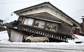 A damaged car lies underneath a collapsed building in Shika town, Ishikawa Prefecture on 8 January, 2024.