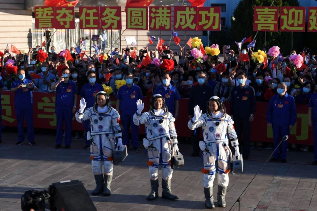 Astronauts Nie Haisheng (R), Liu Boming (C) and Tang Hongbo wave  before boarding the Shenzhou-12 spacecraft before lift off on a Long March-2F carrier rocket at the Jiuquan Satellite Launch Centre in the Gobi desert  on June 17, 2021.