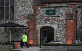 A police officer stands in front of The Mill pub in Salisbury, southern England. Diners are being told to wash their possessions.