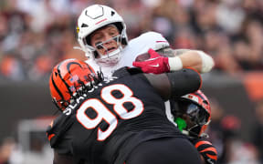 Trey McBride of the Arizona Cardinals is tackled by Demetrius Knight Jr. and T.J. Slaton Jr. of the Cincinnati Bengals, 2025.