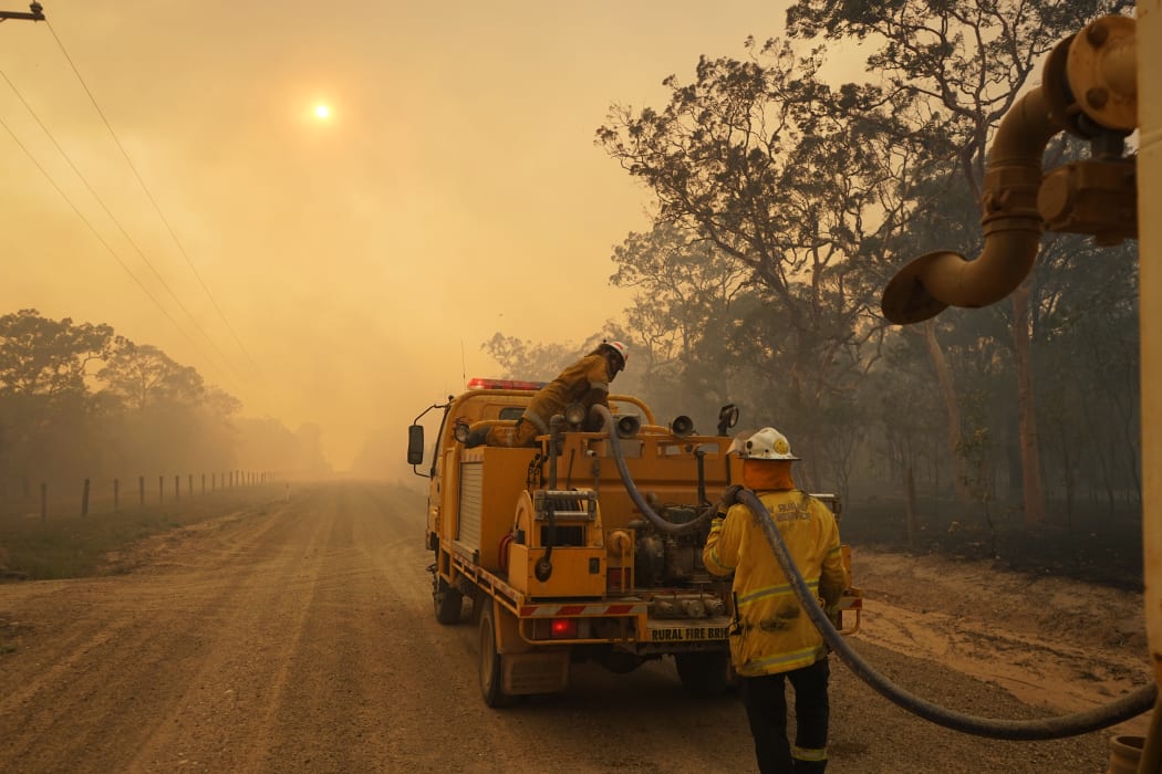 Firefighters refill their water from a water tanker in Pacific Drive in Deepwater National Park area of Queensland.