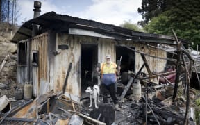 Palmerston man Kevin Lott and his dog, Patch, stand in the remnants of his off-grid container home that went up in flames last week. PHOTO: GERARD O’BRIEN