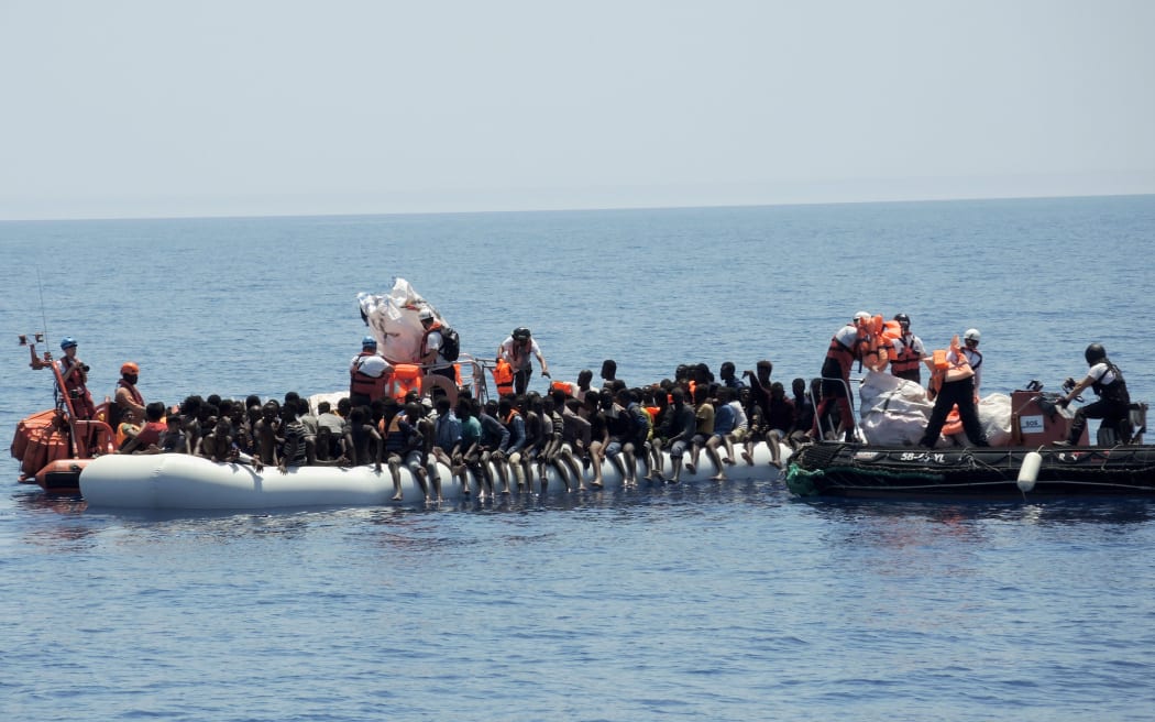 Emergeny personnel of the aid organisations Doctors without Borders and SOS Méditerranée approach an overcrowded rubber dinghy in the Mediterranean, 27 June 2017.