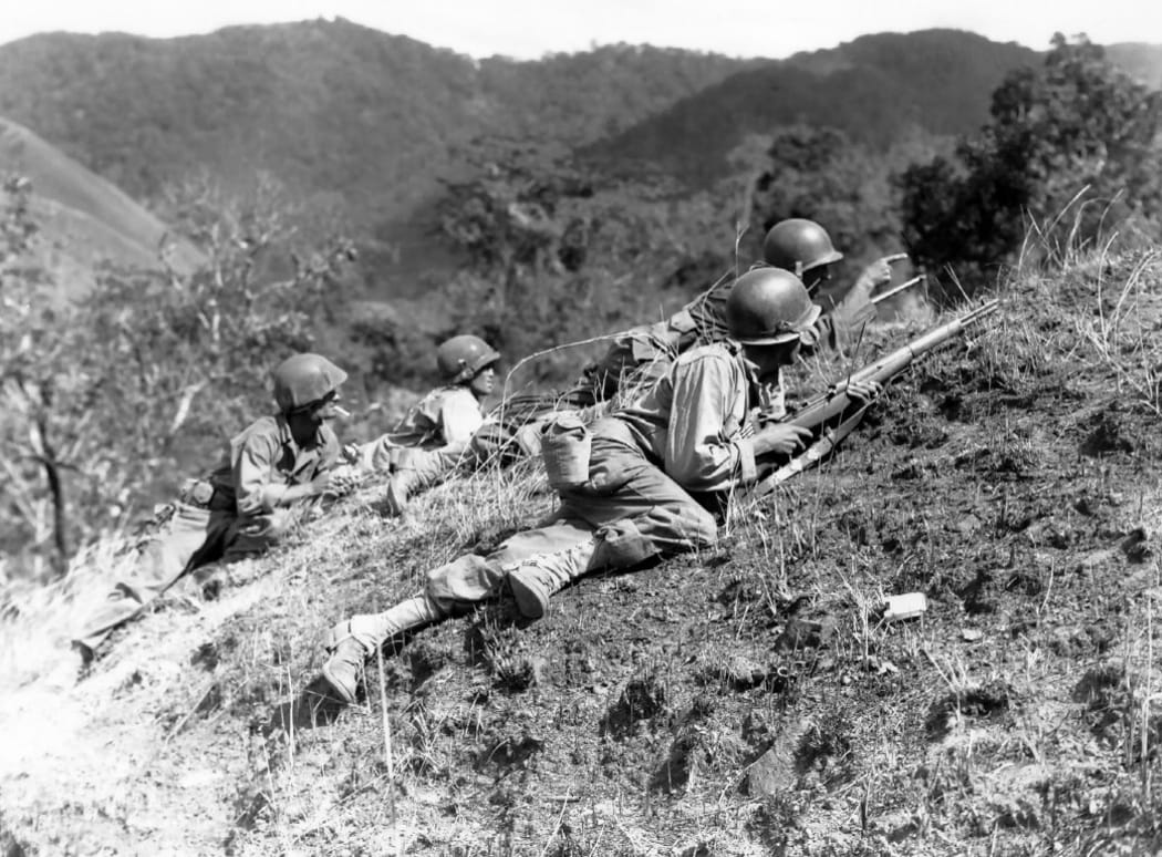 A squad leader points out a suspected Japanese position at edge of Baleta Pass, near Baugio, Luzon, P.I., where troops of the 25th Inf. Div. are in fierce combat with the enemy. 23 March 1945.