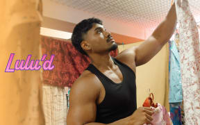 A handsome man hangs up clothing in a shop. Text reads "Lulu'd"
