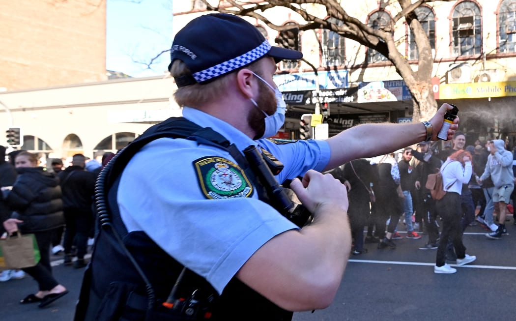 A Police officer uses a spray to disperse protesters during an anti-lockdown rally in Sydney on July 24, 2021, as thousands of people gathered to demonstrate against the city's month-long stay-at-home orders.