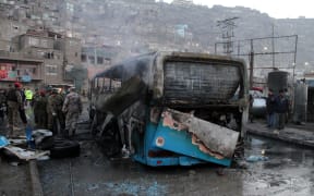 Afghan security personnel inspect a damaged bus at the site of a suicide attack by the Taliban in Kabul, Afghanistan.