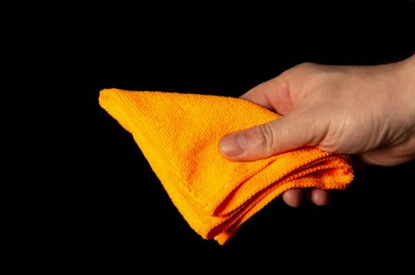 A man holds a bright orange microfibre cloth.