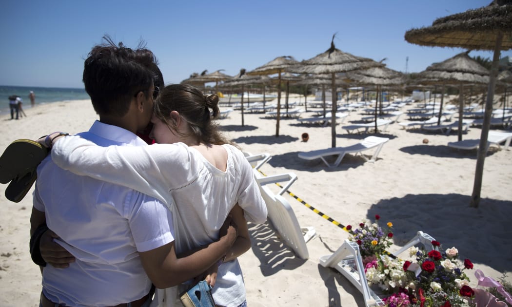 People react at the site of a shooting attack on the beach in front of the Riu Imperial Marhaba Hotel.