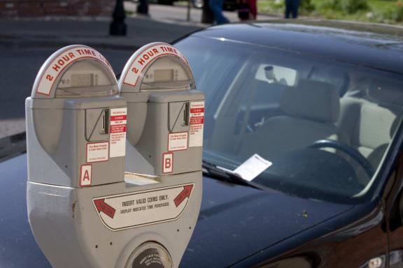 6998921 - parking meter with a car in the background with a ticket on the windshield