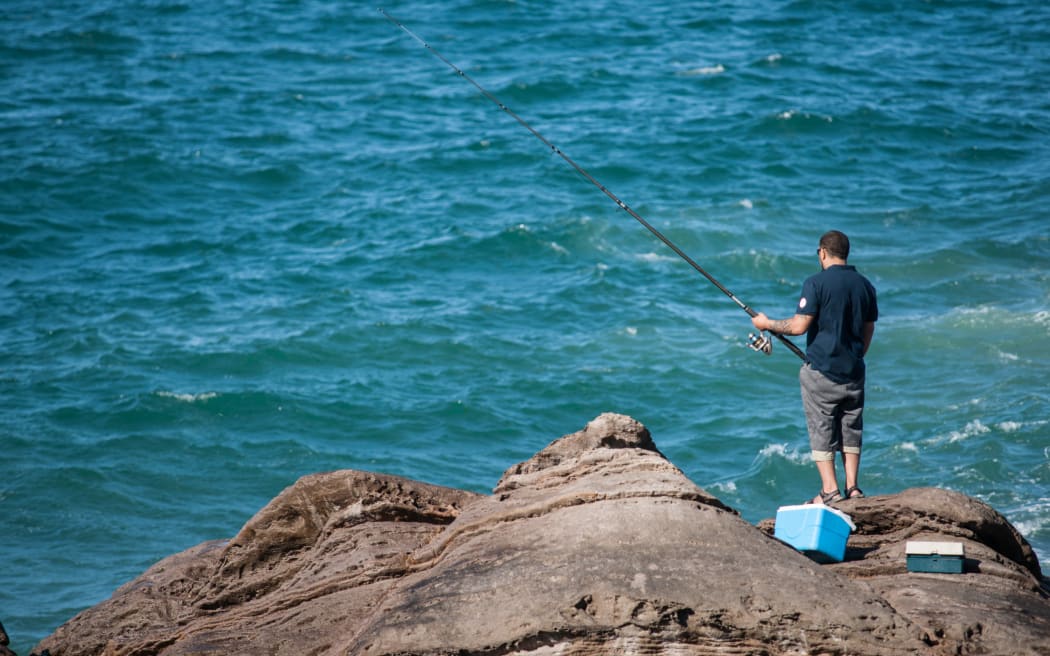 Man rock fishing at base of Mount Maunganui.