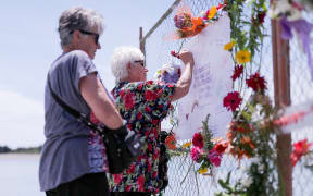 A woman writing a message on the cordon fence that's serving as a makeshift memorial.