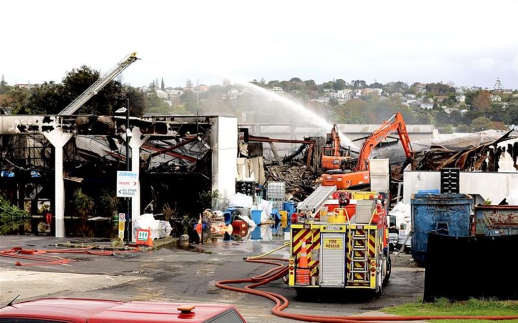Fire crews at the scene of a recycling plant the day after a large fire engulfed the industrial building in Auckland's North Shore.