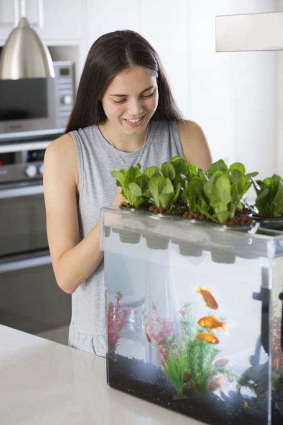 Georgia Lala standing beside one of her aquaponics tanks