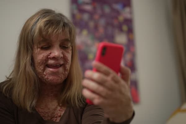 Hayley holding up her phone to chat to her AI companion, Miles.