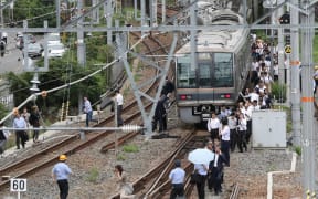 Passengers from a train walk along railroad tracks following an earthquake in Osaka on June 18, 2018.