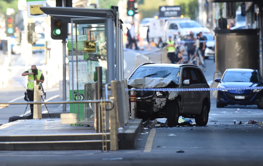 A white SUV sits in the middle of the secen after being driven into pedestrians