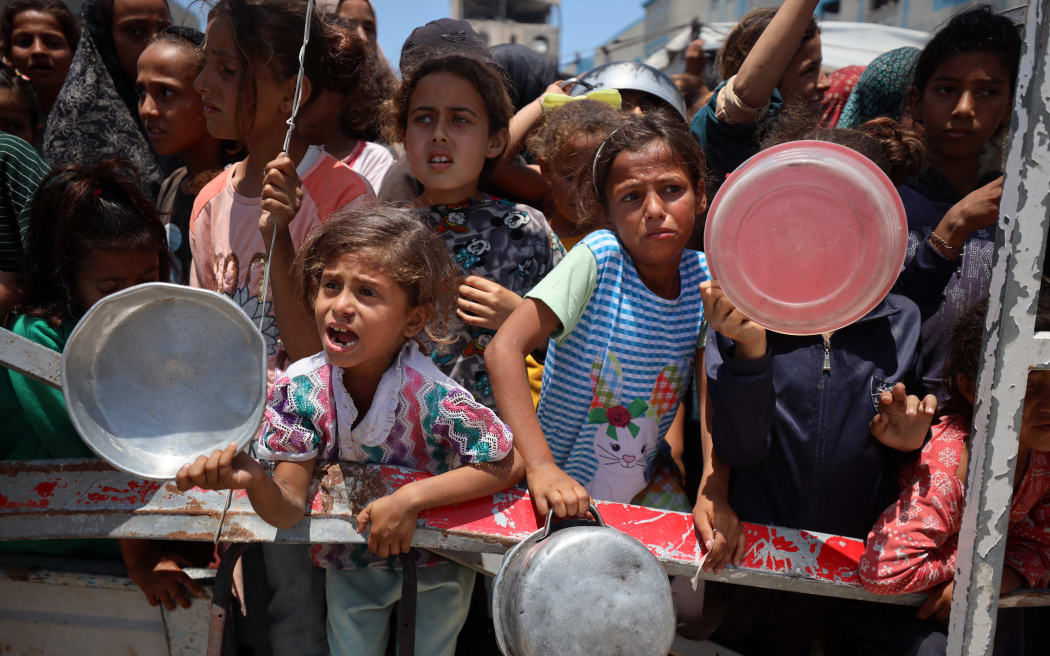 Palestinian children wait with others for food at a distribution point in Gaza City, on June 3, 2025. Israel faces growing condemnation over the humanitarian crisis in the war-ravaged Gaza Strip, where the United Nations warns the entire population faces the risk of famine after no aid is allowed to enter for more than two months. (Photo by Majdi Fathi/NurPhoto) (Photo by MAJDI FATHI / NurPhoto via AFP)