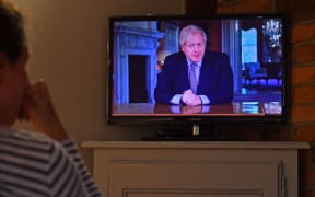 A woman watches Britain's Prime Minister Boris Johnson give a televised message to the nation on 10 May