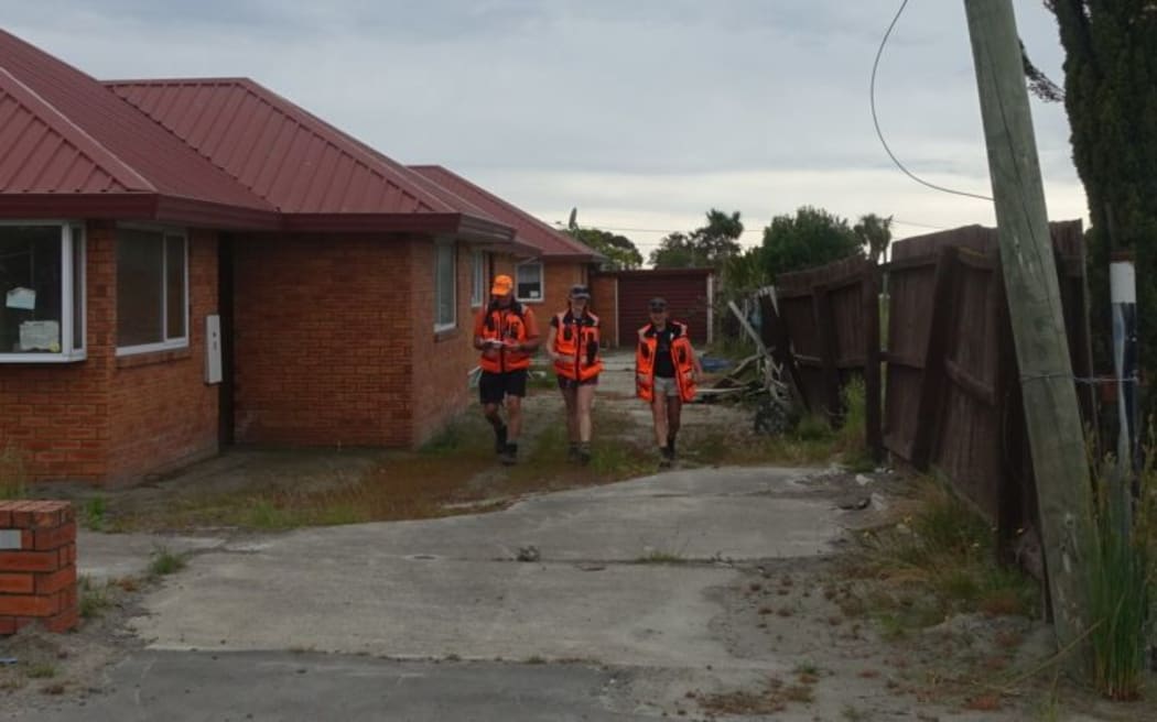 Volunteers (L-R) Daryl Johnson, Deborah Waddingham and Shari Walker search the red zone in Christchurch's Bexley.
