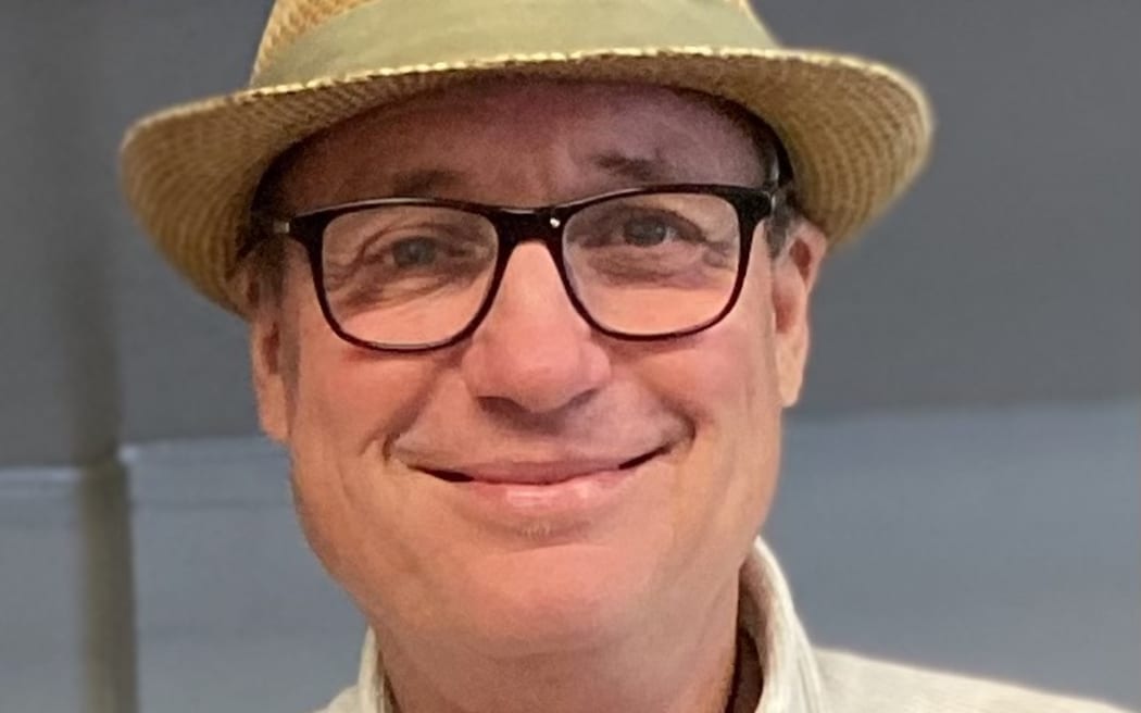 This is a close up photo of Andrew Melville's face. He is wearing glasses with a thin black frame and a straw hat.