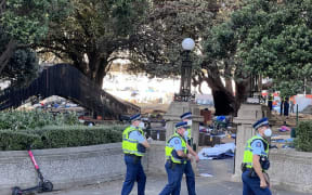 Police walking across a path, with a charred and blackened children's slide in the background.