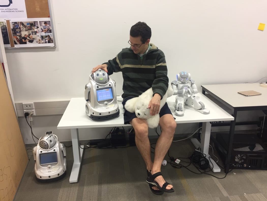 Dr Craig Sutherland with with an iRobi, a Paro and Nao.