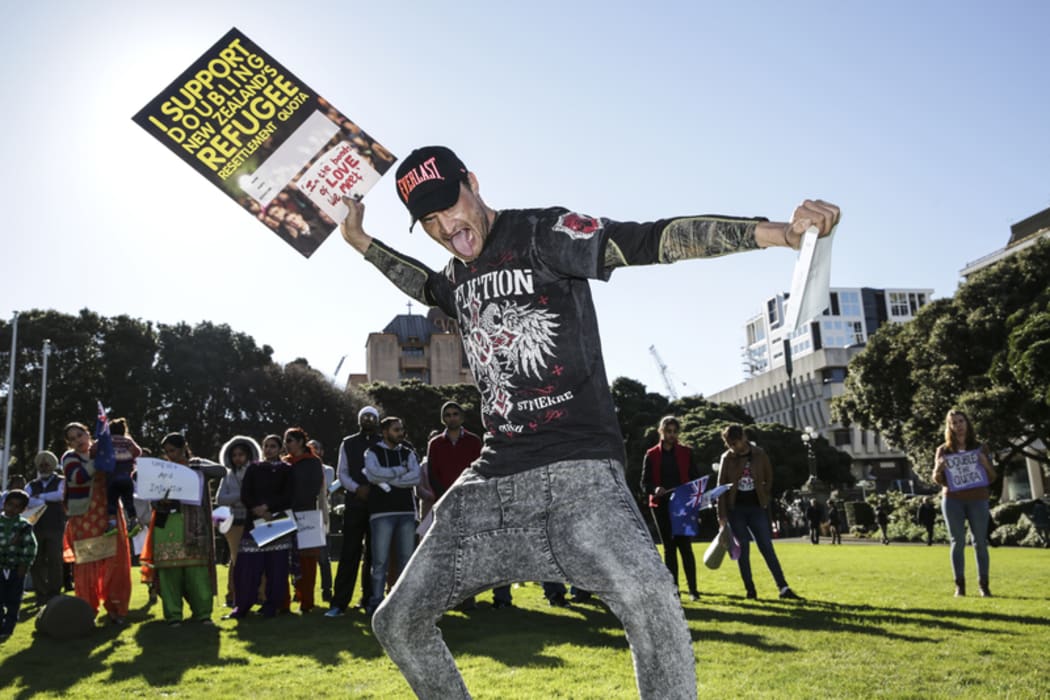Refugee Quote Protest. A man holds a sign saying "I support doubling New Zealand's refugee settlement quota" and the Holy Bible