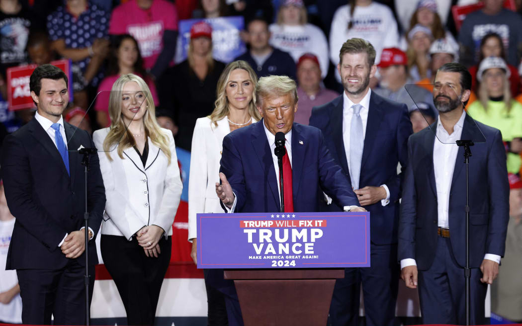 Former US President and Republican presidential candidate Donald Trump speaks (C) alongside Tiffany Trump's spouse Michael Boulos (L), Tiffany Trump (2nd L, co-chair of the Republican National Committee Lara Trump (3rd L), Eric Trump (2nd R) and Donald Trump Jr., during a campaign rally at Van Andel Arena in Grand Rapids, Michigan on November 5, 2024. (Photo by KAMIL KRZACZYNSKI / AFP)