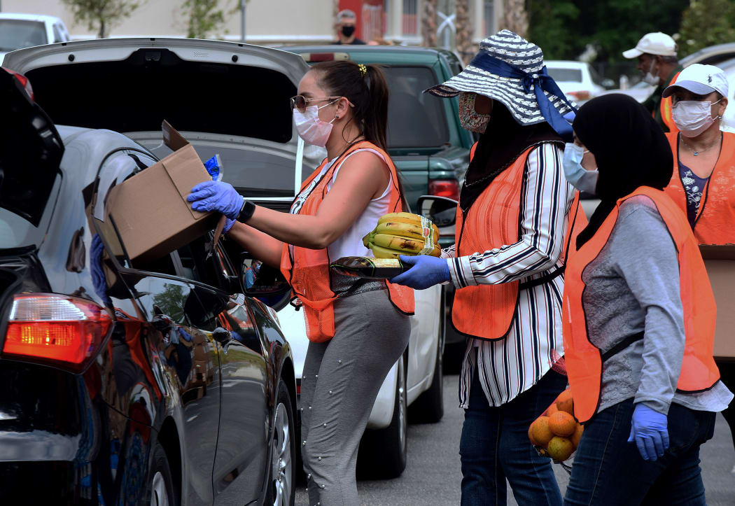Volunteers distribute food to needy families during a drive-thru event on 9 April, Orlando, Florida. The food bank has seen record demand, due to job losses caused by the pandemic.