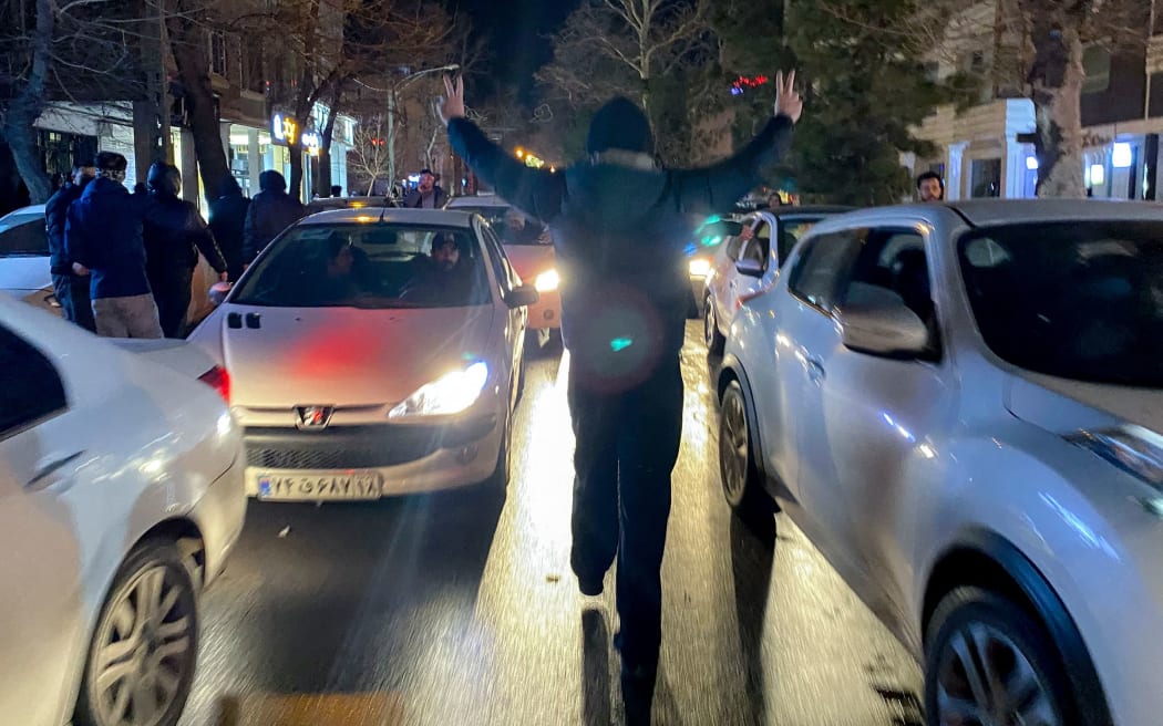 A protester flashes victory signs as traffic slows during demonstrations in Hamedan, Iran.