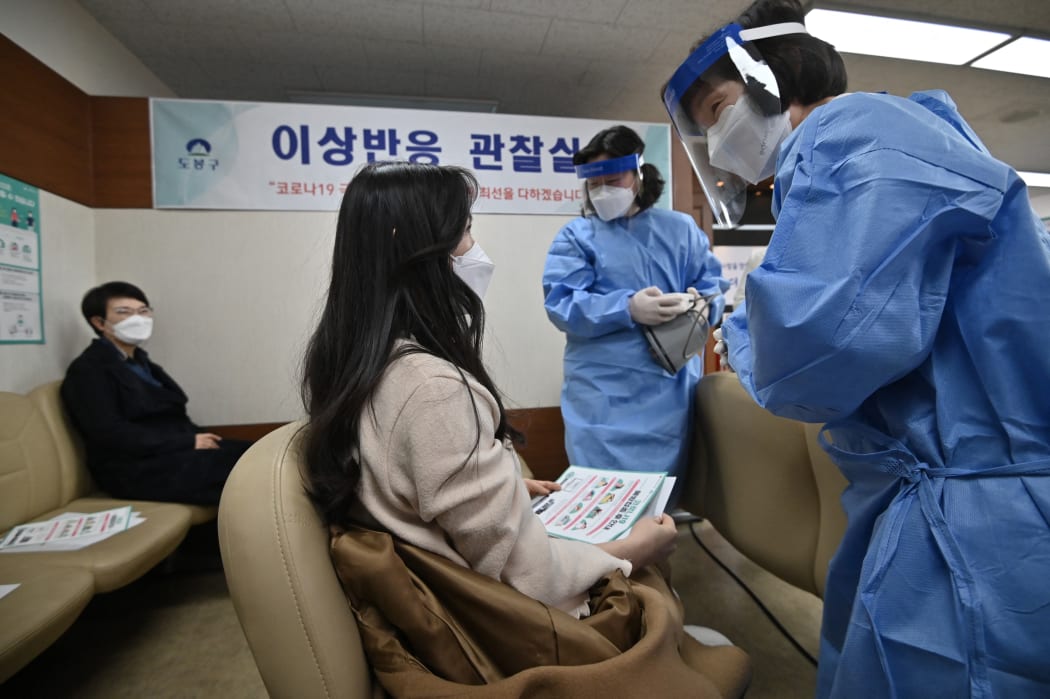 Medical staff check a nursing home worker after receiving the first dose of the AstraZeneca vaccine.