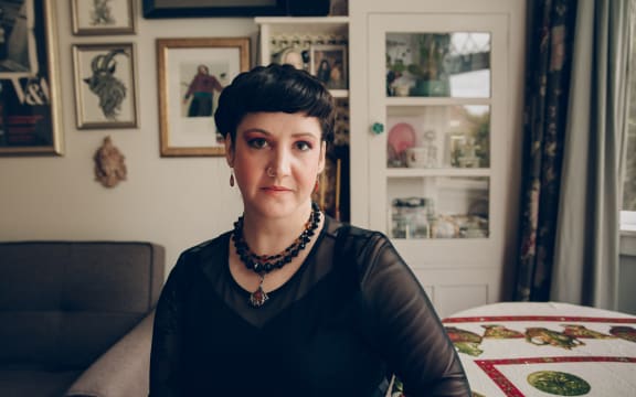 Una Cruickshank - a woman with short black hair and a black top - looks enquiringly at the camera.