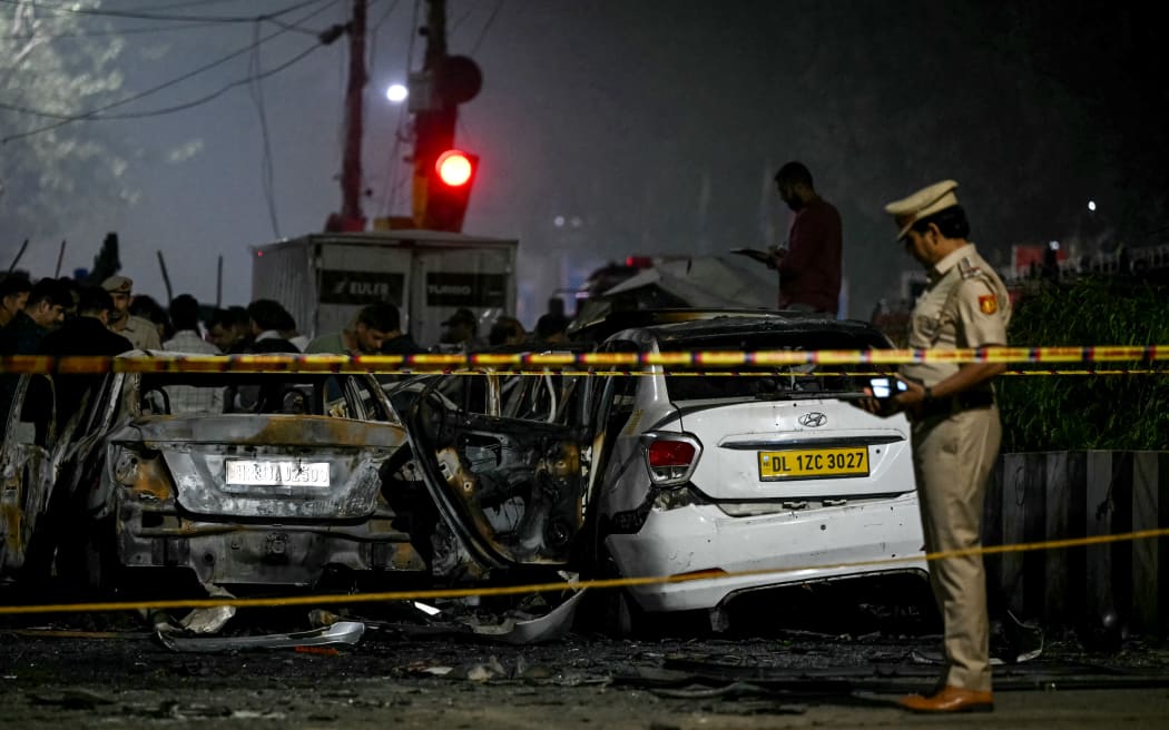 A police personnel inspects charred vehicles at the blast site after an explosion near the Red Fort in the old quarters of Delhi on 10 November, 2025.