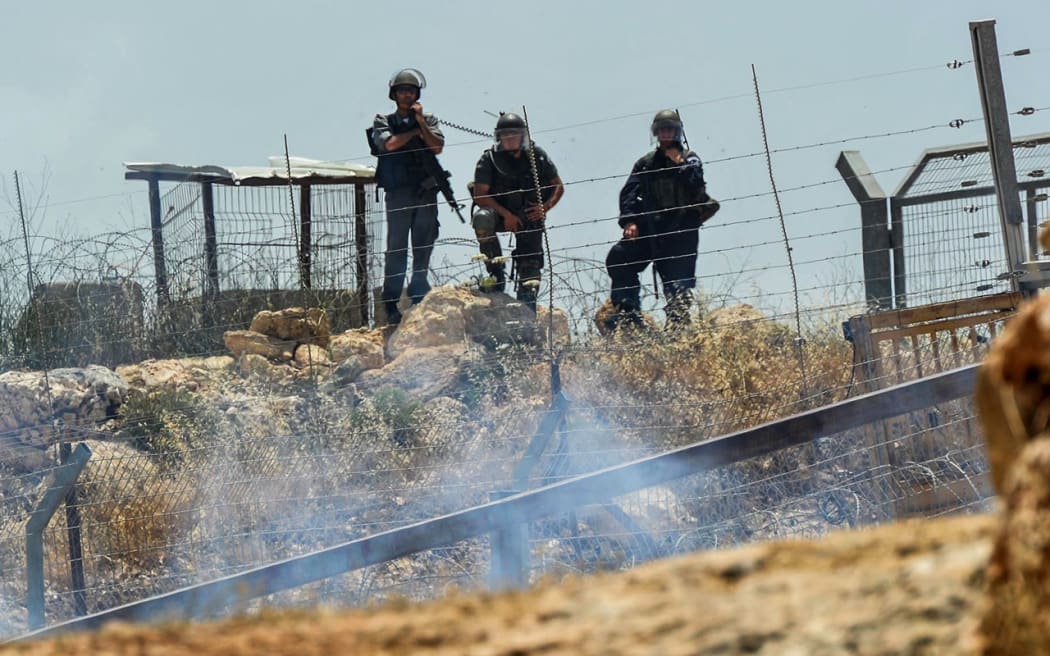 Israel Defence Force soldiers watch the protest after tear gas was fired.