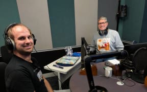 Jesse Mulligan and Scrabble expert Chris Tallman sit in the RNZ Studio. Chris's scrabble board sits between them.