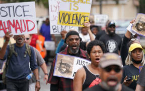 Demonstrators march near the Glynn County Courthouse where the trial for the killers of Ahmaud Arbery is taking place.