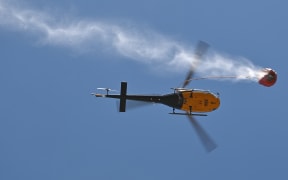 A helicoptor drops water on an out of control bushfire near Taree, 350km north of Sydney on November 12, 2019