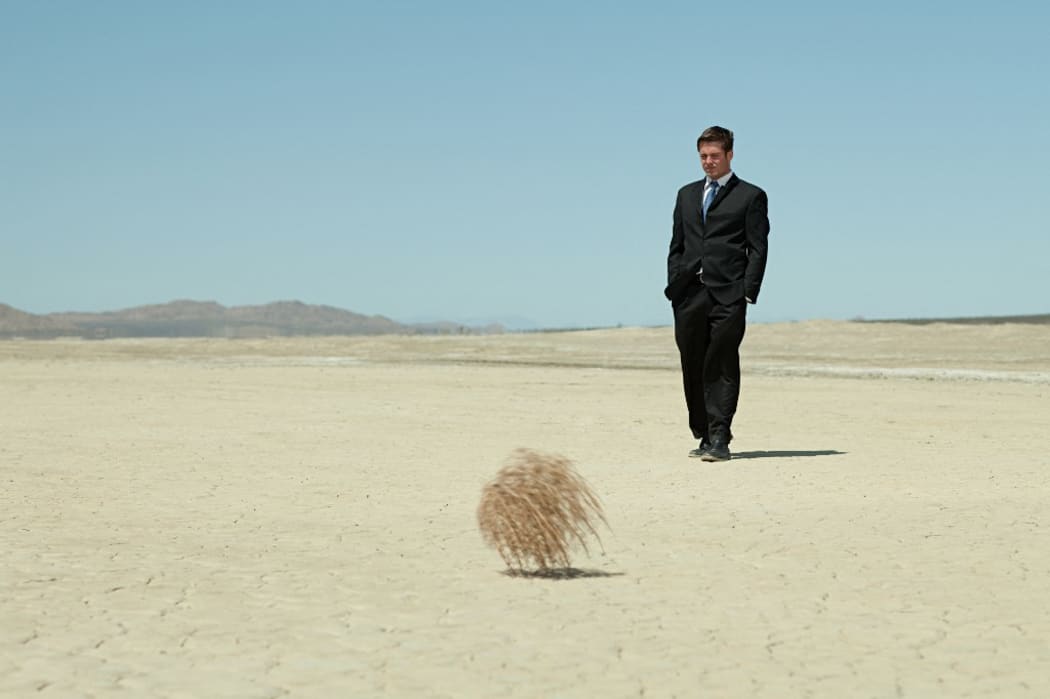 Businessman in desert with tumbleweed (Photo by Christopher Robbins / Image Source / Image Source via AFP)