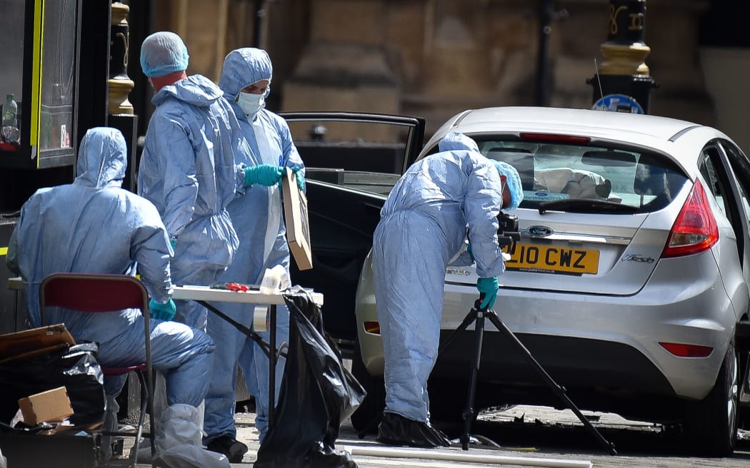 Forensic officers work on the  vehicle that crashed into security barriers outside the Houses of Parliament.