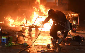 A student tries to extinguish a fire at the entrance of Hong Kong Polytechnic University.