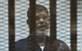 Mohamed Morsi stands behind the bars during his trial in Cairo in 2015.