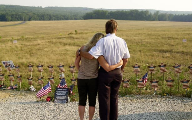 Jeff and Sandy Stewart of Pittsburg, PA, hug each other 11 August 2002 as they look at angels representing the passengers on Flight 93 at the temporary flight 93 memorial overlooking the crash site in Shanksville, PA. US President George W. Bush is to spend the one-year anniversary of the September 11 terrorist attacks by visiting the Shanksville crash site in tribute to the more than 3,000 victims of the attacks, and plans to visit the two other sites hit by the hijacked commercial planes, the White House announced 03 August.AFP PHOTO/Shawn THEW (Photo by SHAWN THEW / AFP)