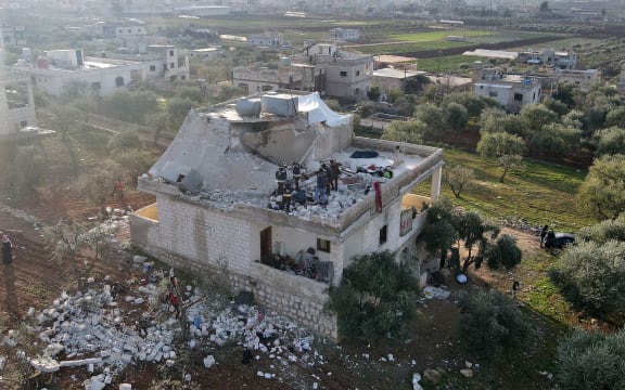 Syrians gather on February 3, 2022 at the scene following an overnight raid by US special operations forces against suspected jihadists in northwestern Syria.