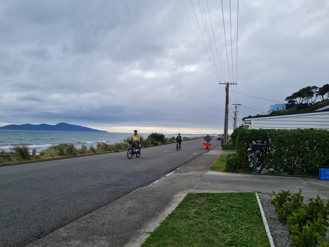 Cyclists ride along the waterfront in Pukerua Bay, a small seaside community