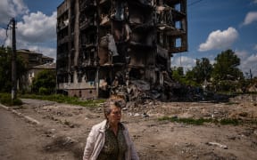 A woman walks past a destroyed apartment building in the town of Borodyanka on 1 June, 2022, amid the Russian invasion of Ukraine.